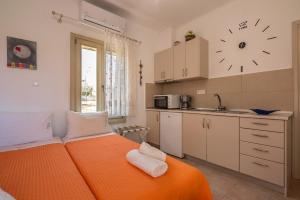 una cama naranja en una cocina con un reloj en la pared en Harmony House, en Kissamos