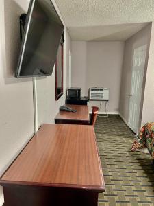 una camera con due tavoli in legno e una TV a schermo piatto di Bradbury Inn a Big Spring