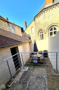 un patio con una mesa y una sombrilla en una valla en L'Insolite en Bourges