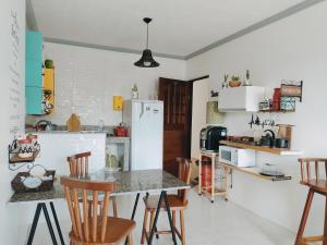 a kitchen with a table and chairs and a refrigerator at Alu Azul 1 in Barra de São Miguel