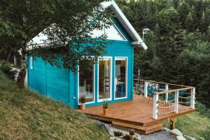 ein kleines blaues Haus mit einer Holzterrasse in der Unterkunft Lazurowe Love - domek na odludziu z widokami in Jaszczurowa