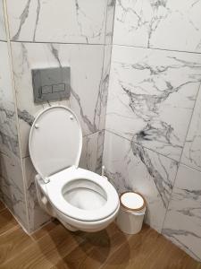 un bagno con pareti in marmo e servizi igienici bianchi. di KLEPALSKI - Mountain Studio a Borovets