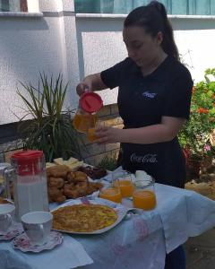 una mujer vertiendo jugo de naranja en una mesa de comida en The White Villa en Poliçan