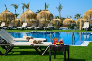 un complejo con piscina, sillas y mesa en Cabogata Beach Hotel, en Retamar