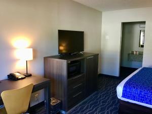 Habitación de hotel con cama y escritorio con TV. en Travelodge Inn & Suites by Wyndham Missoula University Park en Missoula