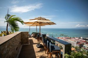 Pinnacle Resorts 179 - Adults Only في بويرتو فايارتا: بار فيه كراسي ومظلات مطله على المحيط