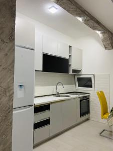 a kitchen with white appliances and a yellow chair at ID apartments in Tivat