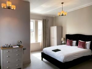 1 dormitorio con 1 cama con sábanas blancas y almohadas rosas en The Rosewood Torquay, en Torquay