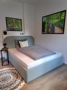 a bed in a bedroom with two pictures on the wall at Waldstadt-Apartments in Iserlohn