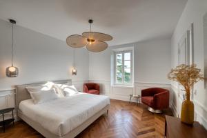 a bedroom with a white bed and two red chairs at L'Iris de Suse in Le Barroux