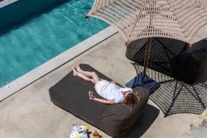 a woman laying on a chair with an umbrella next to a pool at Muro Suites in Ornos