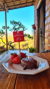 a plate with a chocolate cake and strawberries with a candle at Bangalô do Amor in Serra do Cipo