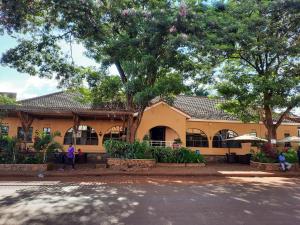 a yellow building with people standing in front of it at Al-Nisaa Hotel and Spa in Jinja
