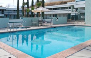 a large blue swimming pool with an umbrella at Siesta Motel in Nogales