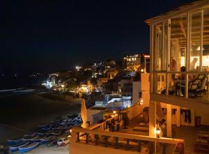 a balcony of a building with a beach at night at L'Auberge Taghazout in Taghazout