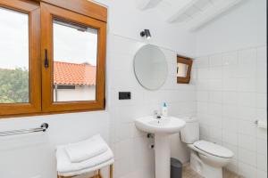 uma casa de banho com um lavatório, um WC e uma janela. em BENEDICTA FAMILY ROOMS em Suances