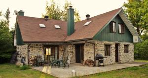 una casa in pietra con tetto verde e patio di Chalet Rustique CRDS Tremblant a Lac-Superieur