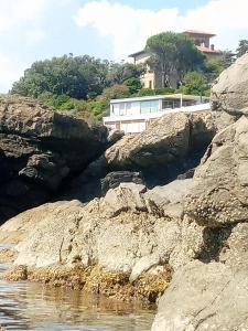 ein Gebäude auf einem Hügel neben einem Wasserkörper in der Unterkunft Hotel La Scogliera in Cavi di Lavagna