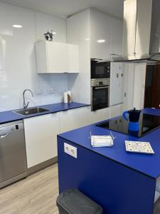 a kitchen with a blue counter top and white cabinets at Patos Beach III - Olas in Nigrán
