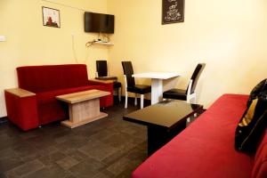 a waiting room with a red couch and a table at Moon Hostel in Prishtinë