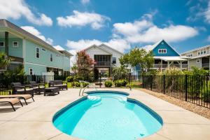 einen Pool mit Stühlen und einem Zaun in der Unterkunft Seashell Cottage by Oak Island Accommodations in Oak Island