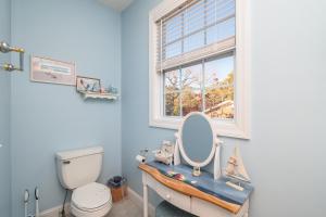 a bathroom with a toilet and a sink with a mirror at Woodlands Wonder by Oak Island Accommodations in Oak Island