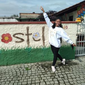 una mujer parada frente a una pared con su brazo en el aire en Hostel Cidade das Flores 2, en Joinville