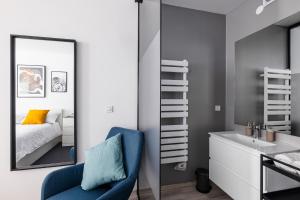 a bathroom with a mirror and a blue chair and a bed at New Central Studio with Parking in Ljubljana