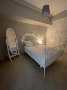 een slaapkamer met een wit bed en een spiegel bij Demi’s garden near the metro of Athens in Athene