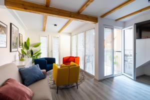 a living room with a couch and chairs and windows at New Central Studios with parking in Ljubljana