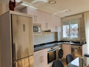 a kitchen with white cabinets and a stainless steel refrigerator at Centro Zaragoza, con parking incluido in Zaragoza