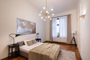 a white bedroom with a bed and a chandelier at Old Riga Modern and Spacious 2 bedroom Apartment in Rīga