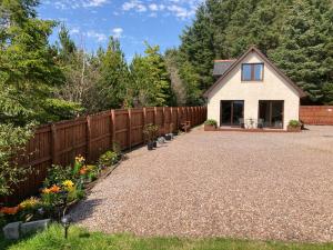 un patio trasero con una valla y una casa en Thistle Do Fort William en Fort William