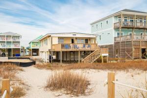 a row of houses on the beach next to the sand at Smart Pelican by Oak Island Accommodations in Oak Island