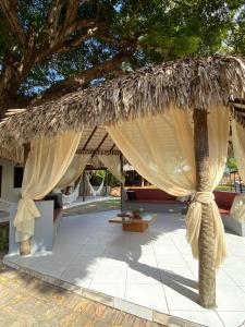 a large straw umbrella with a table and a tree at Pousada Paraiso in Santo Amaro