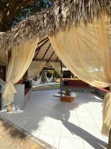 a resort with a thatched roof with a table and a couch at Pousada Paraiso - Santo Amaro Centro - perto de tudo in Santo Amaro