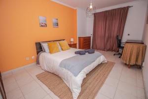 Un dormitorio con una cama grande con paredes naranjas. en Charming Private Rooms in an Apartment A2 Penha - Faro, en Faro