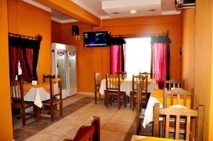 a dining room with tables and chairs and a tv on the wall at Hostel Copacabana La Quiaca in La Quiaca