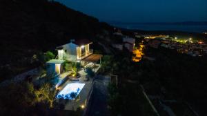 an aerial view of a house with a swimming pool at night at Olive Stone House in Makarska