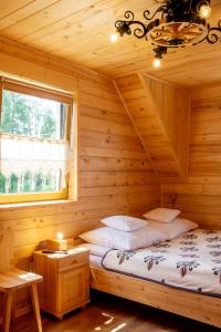 a log cabin bedroom with two beds and a window at Domek Przekolec in Szaflary