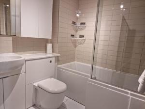 Park View Garden apartment في Salfords: حمام مع مرحاض وحوض استحمام ومغسلة