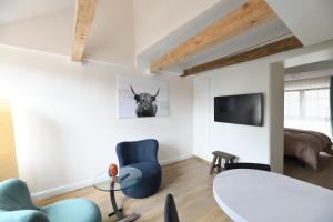 a living room with a blue chair and a tv at Das schiefe Haus - Wohnung "Weinlage" in Heppenheim an der Bergstrasse