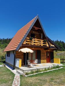 a log cabin with a table and chairs and an umbrella at Vikendica Dana in Mitrovac