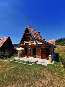 a log cabin with a patio in a field at Vikendica Dana in Mitrovac