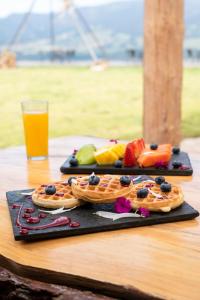 dos platos negros con gofres y fruta en una mesa en Neusa Hills Glamping, en Tausa Viejo