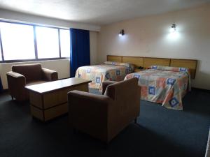 a hotel room with two beds and two chairs at Hotel Lerma in Lerma de Villada