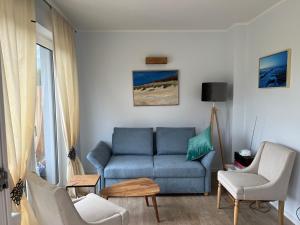 a living room with a blue couch and chairs at Haus Luca Fuhlendorf in Fuhlendorf