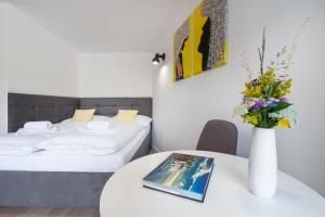 a room with two beds and a table with a vase with flowers at Apartmány LAMA in Nižné Malatíny