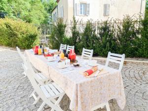 een lange tafel met witte stoelen en eten erop bij LE COTTAGE DU PARC in Chambéon