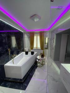 a white tub in a bathroom with purple lighting at Apartament "Prezydencki" Centrum z dużą wanną dla Dwojga in Gniezno
